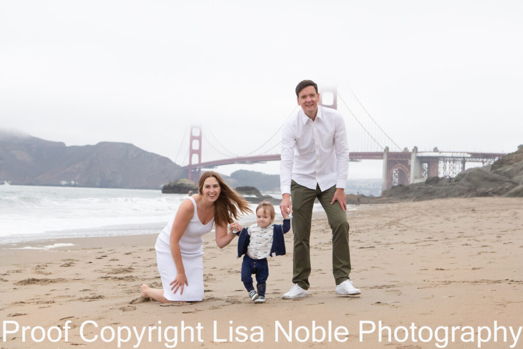 Family at photography session standing on Beach with Golden Gate Bridge in Background
